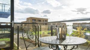 Tailored Stays - De Havilland House في كامبريدج: طاولة على شرفة مع كأس من النبيذ