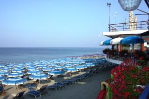 a group of chairs and umbrellas on the beach at Apartments Arcobaleno in Deiva Marina