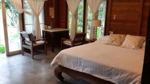 1 Schlafzimmer mit einem Bett, 2 Stühlen und einem Schreibtisch in der Unterkunft BanJankapor in Kaeng Kachan