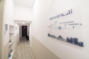 un couloir doté d'un mur blanc et d'un panneau. dans l'établissement B&B Università, à Naples