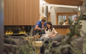 a man and a woman sitting in front of a fireplace at Aktiv & Genusshotel Lodenwirt in Vandoies