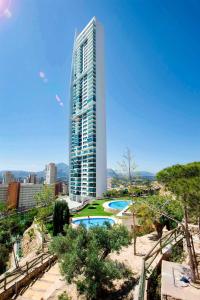 een hoog gebouw met een zwembad ervoor bij Highrise apartment with private terrace & sea views - 34th floor in Benidorm