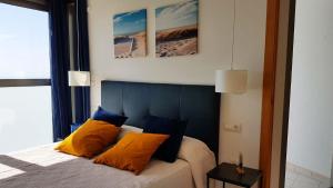 een slaapkamer met een bed met oranje en blauwe kussens bij Highrise apartment with private terrace & sea views - 34th floor in Benidorm