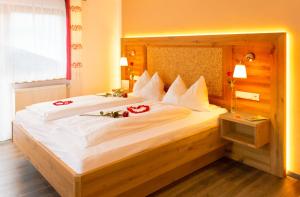 ein Schlafzimmer mit einem großen Bett mit roten Rosen darauf in der Unterkunft Pension Schuasterhof in Bodenmais