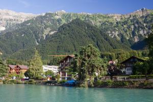 a village on a river with mountains in the background at Seehotel Bönigen in Bönigen