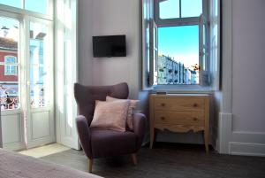 a bedroom with a chair and a dresser with a window at Guest House Santa Clara in Coimbra