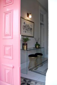 a pink door in a hallway with two stools at Guest House Santa Clara in Coimbra