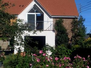 une maison blanche avec une fenêtre et quelques fleurs dans l'établissement La Grange, à Foncquevillers