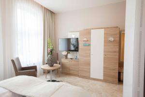 a bedroom with a bed and a tv and a table at Ostseehotel Warnemünde in Warnemünde