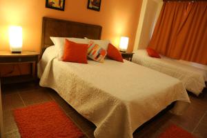 1 dormitorio con 2 camas con almohadas de color naranja y 2 lámparas en Hotel Bulevar, en Paysandú