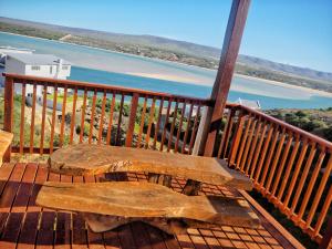 una panchina di legno seduta su un ponte con vista sull'acqua di Net Net Holiday Home a Witsand