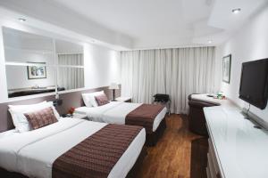 a hotel room with two beds and a flat screen tv at Hotel Golden Park Campinas Cambuí By Nacional Inn in Campinas +28 photos
