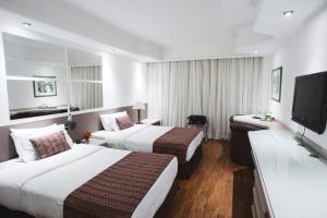 a hotel room with two beds and a flat screen tv at Hotel Golden Park Campinas Cambuí in Campinas