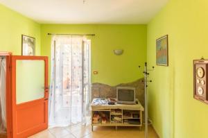 Habitación con paredes verdes, TV y puerta. en Casa Vacanza Il Leonpardo, en Tuscania