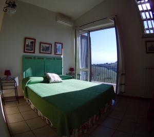 a bedroom with a green bed and a large window at Agriturismo Valle Siriaca in Castelnuovo di Porto