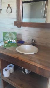 a bathroom sink sitting under a mirror next to a wooden table at Pousada Estalagem da Colina in Cambará
