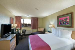 a hotel room with a bed and a flat screen tv at Oxford Suites Lancaster in Lancaster