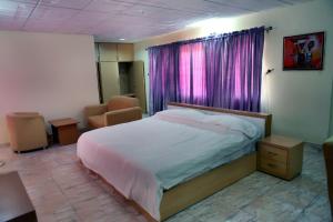 a bedroom with a bed and a window with purple curtains at Nspri Guest Houses in Lagos