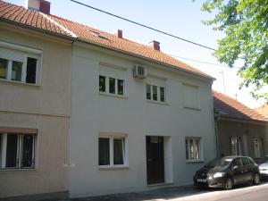 a white house with a car parked in front of it at Jazzy Apartment Zagreb in Zagreb