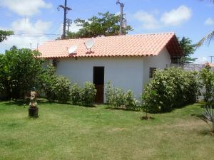 a small white house with a red roof at Chalé Água de Coco in São Miguel dos Milagres