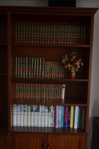 un estante de libros lleno de libros y un jarrón con flores en Casa Pilar, en Cee