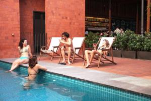un grupo de mujeres sentadas en sillas junto a una piscina en Villa 25 en Río de Janeiro