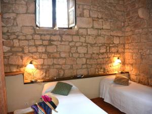 two beds in a room with a stone wall at Antica Dimora San Filippo in Modica