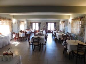 jadalnia ze stołami, krzesłami i oknami w obiekcie Akrothea Hotel w mieście Goura