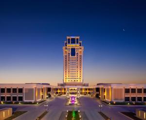 a large building with a lit up tower at night at Divan Erbil Hotel in Erbil