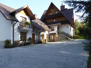 duży biały dom z ceglanym podjazdem w obiekcie Pokoje i apartamenty pod Jaworzyną w Koninkach w mieście Koninki