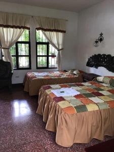 a bedroom with two beds and two windows at La Chacra de Joel Hotel in Huehuetenango