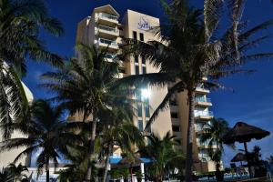 a hotel with palm trees in front of it at Salvia Condominio in Cancún