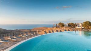 basen z krzesłami i ocean w tle w obiekcie Salobre Villas Deluxe w mieście Salobre