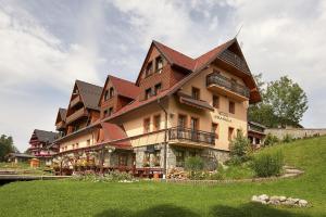 a large building on top of a green field at Penzion Krasula in Ždiar