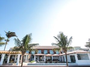 um edifício com palmeiras em frente em Hotel Premium Recanto da Passagem em Cabo Frio