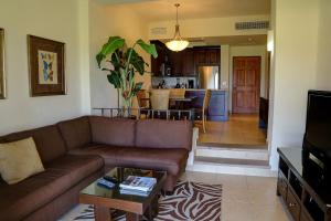 sala de estar con sofá marrón y cocina en Dunas 102, en Cabo San Lucas