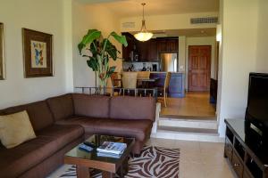 a living room with a brown couch and a kitchen at Dunas 102 in Cabo San Lucas