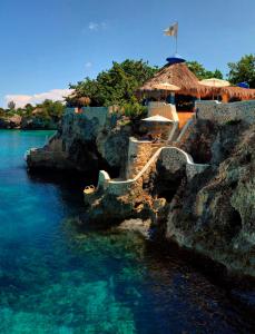 a resort with a stairway to the water and a beach at The Caves in Negril