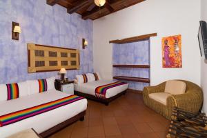 um quarto com 2 camas e uma cadeira num quarto em Hotel Boutique Las Carretas em Cartagena das Índias