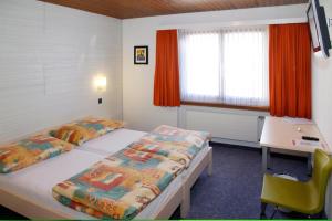 a room with two beds and a desk and a window at Hotel Krone in Attinghausen +35 photos