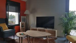 a living room with a flat screen tv and a table at Le Loft de Genas entre Eurexpo et St Exupéry in Genas