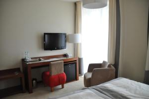 a hotel room with a bed and a tv and a chair at Hotel Atrium in Elblag