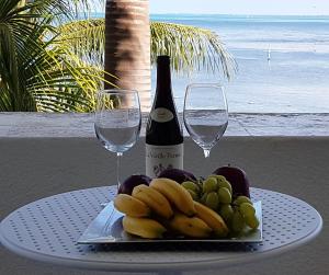 a table with a plate of fruit and wine glasses at Departamento frente al Mar - Kiara in Canc&uacute;n