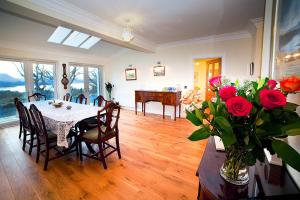 a dining room with a table and a vase of roses at Muldoanich in Gairloch