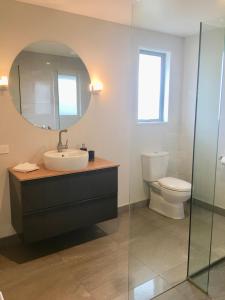 a bathroom with a sink and a mirror and a toilet at Minaret Ridge Retreat in Wanaka