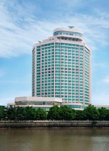 een groot gebouw met veel ramen naast een rivier bij Ramada by Wyndham Pearl Guangzhou-Canton Fair Free Shuttle Bus in Guangzhou