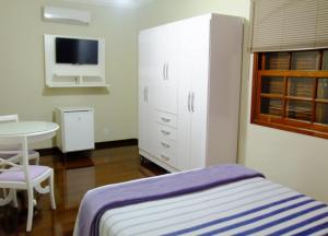 1 dormitorio con cama, mesa y armario en Pousada Apricare, en Cabo Frío