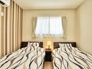 deux lits dans une petite pièce avec une fenêtre dans l'établissement Cottage Sea Wind Nakijin, à Nakijin