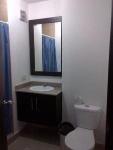 a bathroom with a toilet and a sink and a mirror at Arena Plaza Tonsupa in Tonsupa