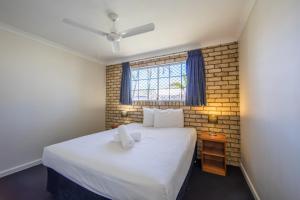 a bedroom with a large white bed with a window at Caboolture Motel in Caboolture